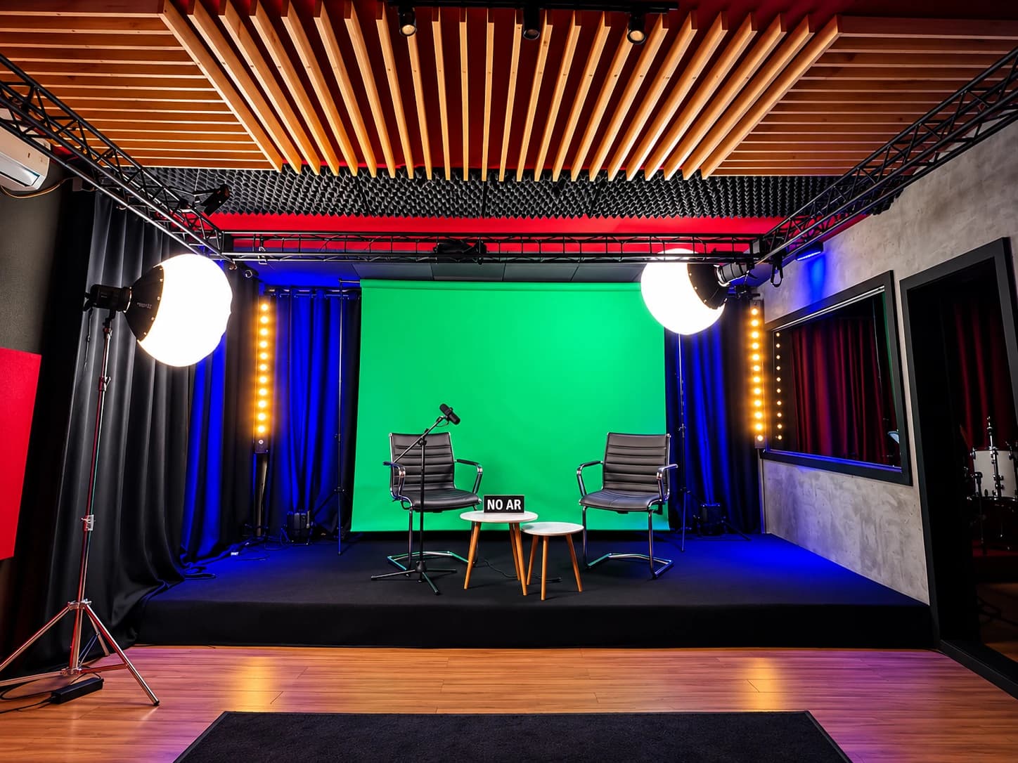 Estúdio com fundo verde de chroma key, cadeiras, microfone e iluminação
