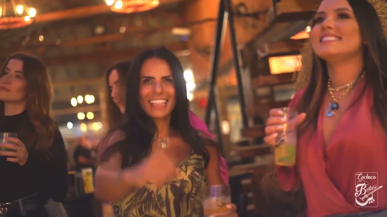 Mulheres sorrindo com copos na mão em um bar de madeira iluminado