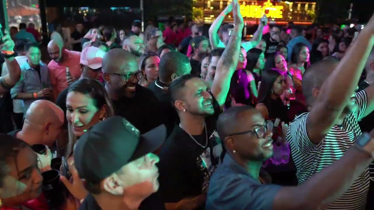 Plateia animada de braços erguidos, sorrindo, em um show ao ar livre à noite