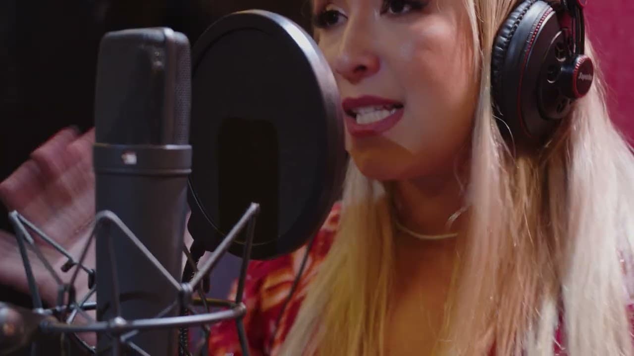 Mulher de cabelo loiro e fones de ouvido cantando diante de um microfone de estúdio com filtro anti-pop
